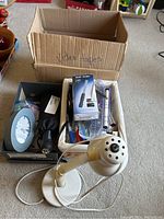 Photo of a white gooseneck desk lamp, pens, clips, and other office supplies in a box labeled 'Video tapes'