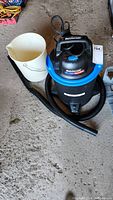 Mastervac shop vacuum beside white plastic pail on floor showing the overall lot content.