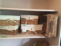 Photo showing multiple wicker baskets on a white shelf, some with beige liners tied with bows, medium and small rectangular shapes