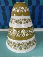 Four Pyrex Crazy Daisy green and white flower mixing bowls nested stacked inside each other, showing decorative floral patterns and size progression.