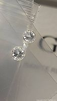 Close-up of two round faceted moissanite stones showing clarity and cut.