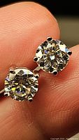 Close-up photo of two round brilliant cut moissanite earrings showing prong setting and high clarity stones.