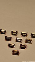 Ten small rectangular faceted sapphires arranged in rows on a plain background showing color and clarity.