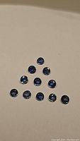 Natural round cut denim blue sapphires arranged on a flat surface showing size and color.