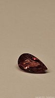 Pear-shaped pink tourmaline gemstone with visible faceting and internal characteristics under natural light.