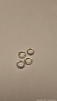 Photo of four silver-colored metal jump rings laid on neutral background.