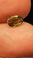 Close-up photo of 1.11ct oval cut sapphire showing chartreuse green yellow color on fingertips