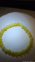 Close-up photo of natural bright yellow lemon jade beads forming a stretchy bracelet.