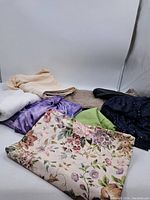 Photo showing assortment of fabric pieces including floral print, solid colors, and textured fabrics arranged on white background.