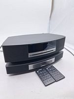 Front view of stacked Bose Wave Music System main unit and 4-disc CD changer with two remotes placed in front