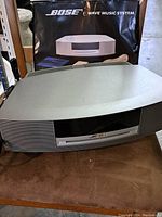 Bose Wave Music System main unit in front of original packaging, power cord visible