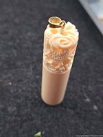 Close-up of the carved cylindrical pendant showing detailed dragon carving and 14k gold bail mounted on top.