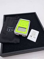 View of Creative Zen portable media player, black pouch, and battery inside presentation box.