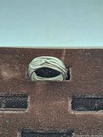 Front view of the custom silver ring showing intertwined band design on a brown display pad.