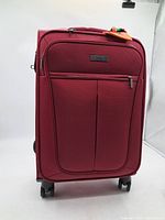 Front view of red Globe Trotter suitcase with handle and front pocket.