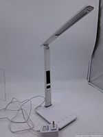 Full side view of the white Ottlite desk lamp showing adjustable arm and power cord with plug.