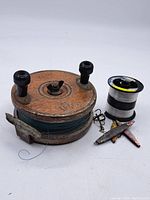 Vintage Peetz wooden fishing reel with fishing line spool, two sinkers, and clip.