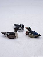 Three small decorative duck decoys on a white surface showing size and color variation.