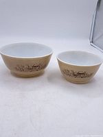 Shows two off-white Pyrex mixing bowls side by side with mushroom pattern on the exterior.