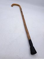 Full view of the wooden cane showing curved handle and rubber tip