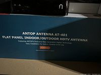 Box of the Antop AT-401 flat panel indoor/outdoor HDTV antenna showing product name and some product features including 60 miles range.