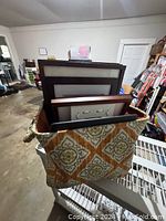 Multiple wooden finish picture frames in assorted sizes placed vertically in a decorative fabric basket with geometric pattern.