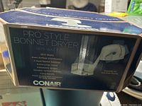 Box showing product details for Conair Pro Style Bonnet Dryer with 1875 watt power and features like adjustable height and variable airflow.