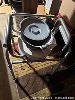 Photo showing the top view of the elderly potty chair with the removable bucket and part of the metal frame visible.