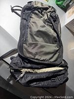 Front view of hiking backpack showing zippered compartment with shoulder straps stored inside.