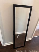 Full view of the mountable full-length mirror with black frame, standing against a wall.