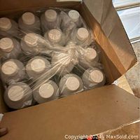 Open box showing 16 one-quart white plastic bottles with white caps arranged and secured with plastic wrap.