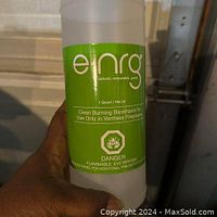 Close-up photo of single 1 quart bottle of e-NRG bioethanol fuel with green label showing product details and safety warnings, held in hand.