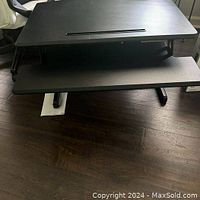 Black Seville AirLift Pro sit-stand desk converter showing the main and keyboard surfaces and slot for holding items upright on the main surface.