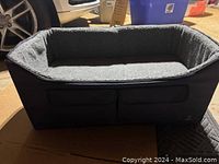 Photo showing the front and side view of the grey travel dog bed with soft interior and zipper storage compartments beneath