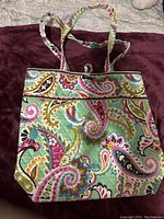 Front view of multi-color paisley patterned Vera Bradley tote bag with handles and zipper closure.
