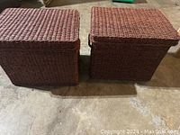 Two rectangular wicker file baskets with lids, placed side by side on a concrete floor.