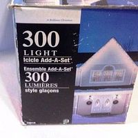 Close-up photo of the 300 Light Icicle Add-A-Set box showing branding, product name, and image of a house decorated with the lights.