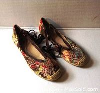 Pair of ladies patterned fabric flats viewed from front showing multicolored pattern and lace-up design.