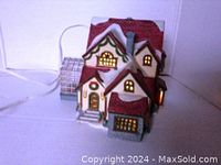 Front and lit view of ceramic Christmas house including attached greenhouse with electric light inside.