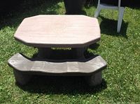 Front view of the kid's picnic table on grass, showing the octagonal table top and attached benches.