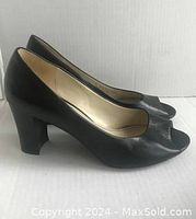Side view of one black leather open toe pump showing the shape and height of the chunky heel.