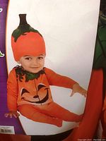 Toddler modeling the pumpkin costume showing the front design and hat.