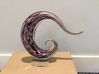Front angle view of the purple swirled Murano glass sculpture showing the swirl shape and color pattern.