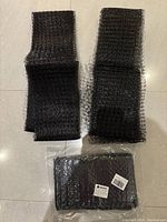 Photo of two large folded black netting pieces and one unopened pack of black netting