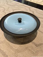 Photo showing the closed casserole with light blue enameled lid and black knob.