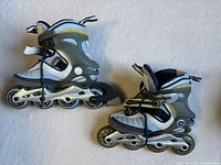 Side view of pair of inline roller blades, blue and gray color with four wheels and adjustable straps.