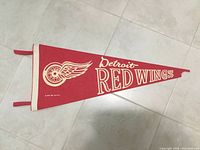 Full view of the Detroit Red Wings red hockey pennant with white winged wheel logo and 'Detroit RED WINGS' text