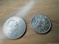 Obverse and reverse images of the 1965 Canadian Silver Dollar and 1965 British Churchill Crown coins showing portraits and designs.