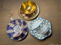 Three cups with saucers from above showing distinctive patterns and gold accents.