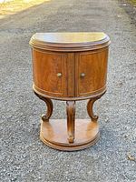 Front view of the small mahogany cabinet showing curved doors and ornate legs.